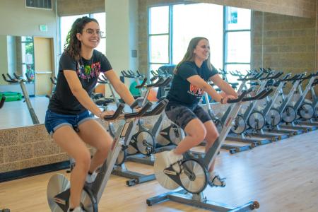 Students smiling while cycling on cycling machines in the SSU Recreation Center